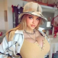 Dana Hamm is wearing yellow shirt, chain over coat and cap or smiling while posing for the picture