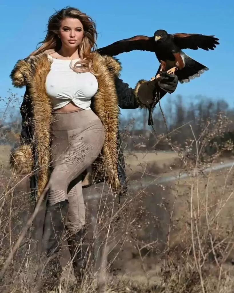 Dana Hamm is wearing white shirt over coat and holding the eagle while posing for the picture