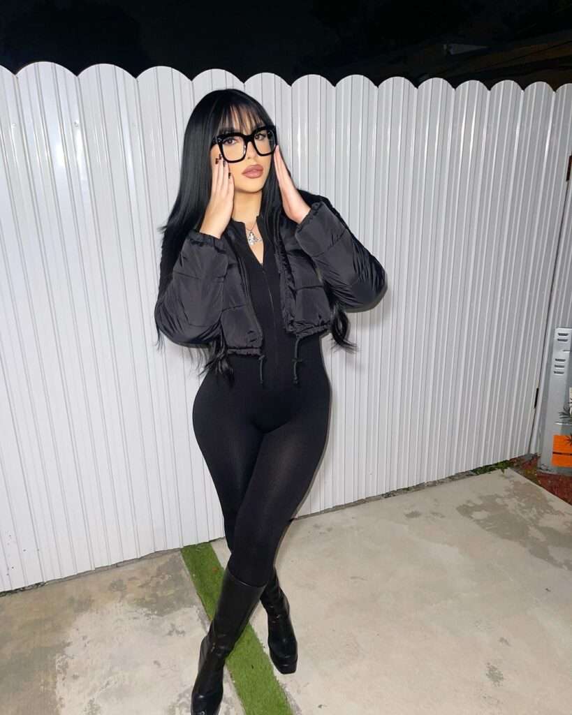 Itsashxmarie is wearing black dress over jacket and glasses and posing for taking the picture