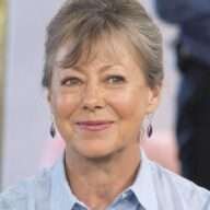 Jenny Agutter is wearing sky blue dress and earrings or smiling while posing for the picture