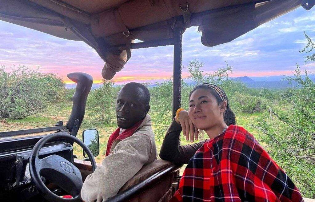 Danielle Kang in the black and red contrast outfit while taking a photo in the jeep with the driver