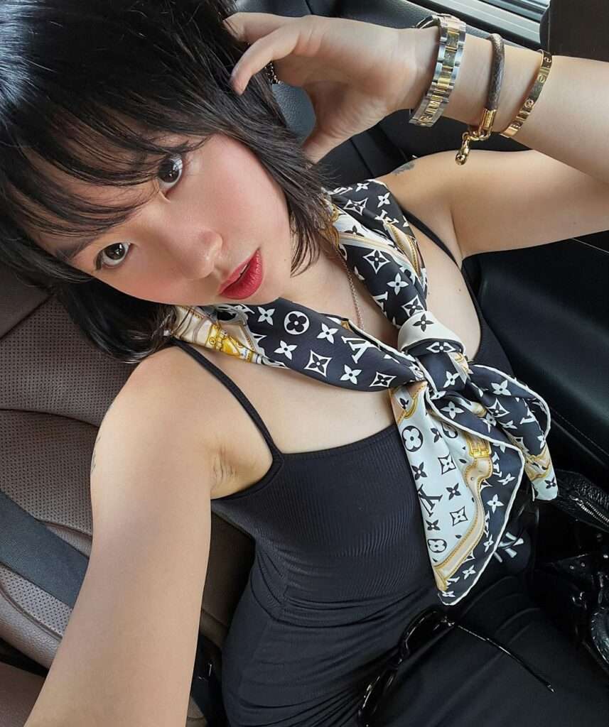 Fake dre in the black stripped top pair with printed scarf and bangles while taking a selfie in the car