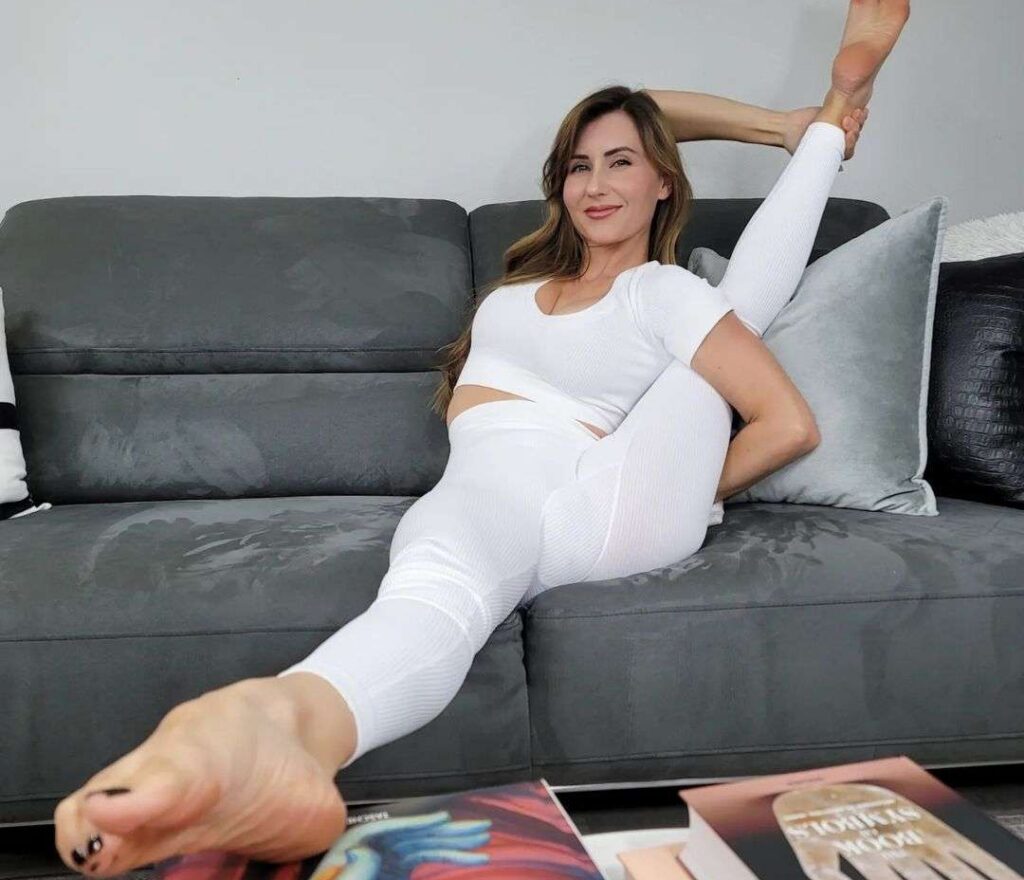 Jamie Marie in the white 2- piece outfit while practising yoga and smiling towards camera