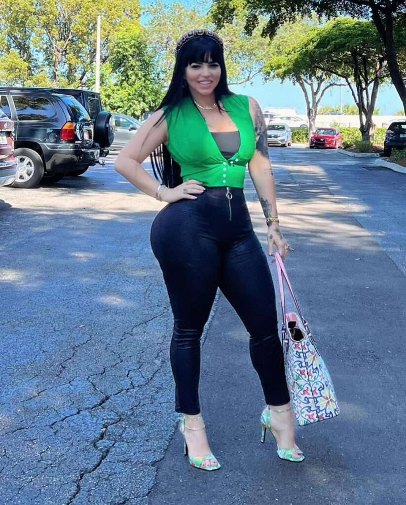 La Mariposa in the black green top pair with black leggings and high heel sandals while smiling towards camera