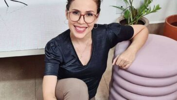 Ráisa Guerra in the black silk shirt pair with matching pants and black shoes while smiling towards camera
