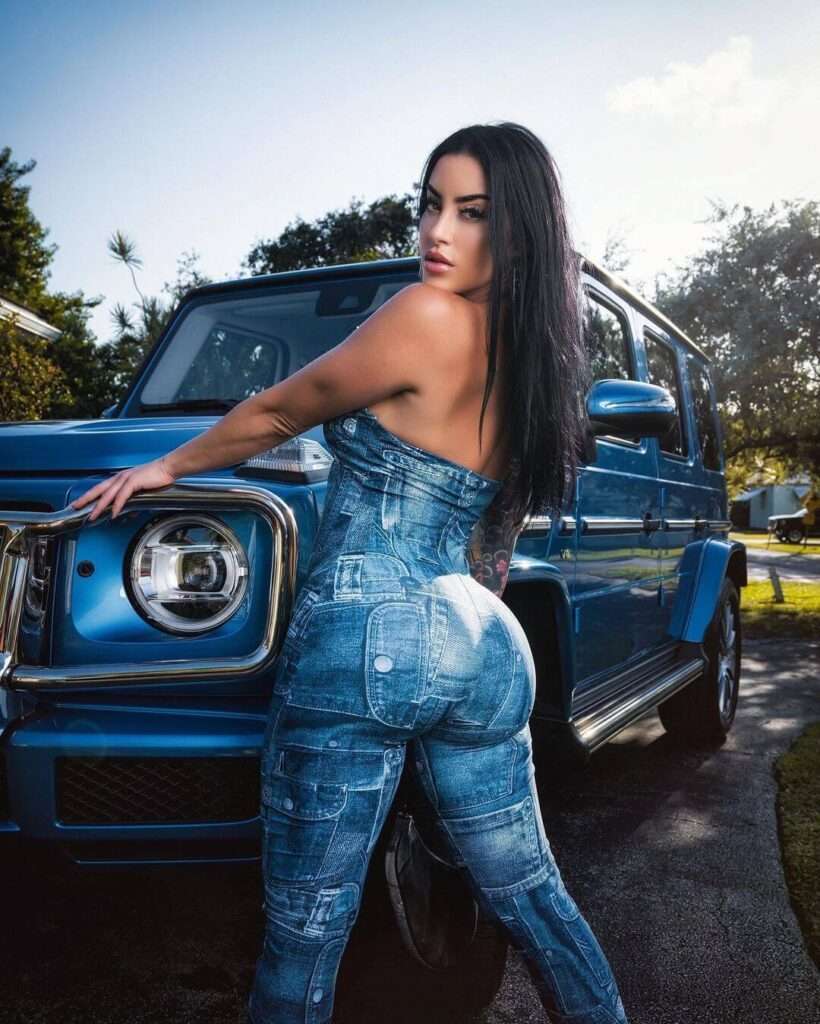 Alysia Magen is wearing blue jeans dress and standing besides a car or posing for the picture
