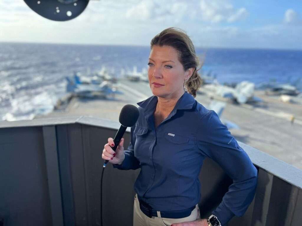 Norah O'Donnell is wearing blue shirt and holding the mike or posing for the pictrue