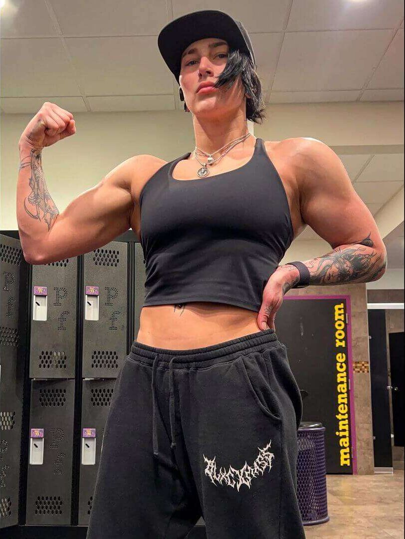 Rhea Ripley is wearing black shirt over trouser and cap or posing while taking the picture
