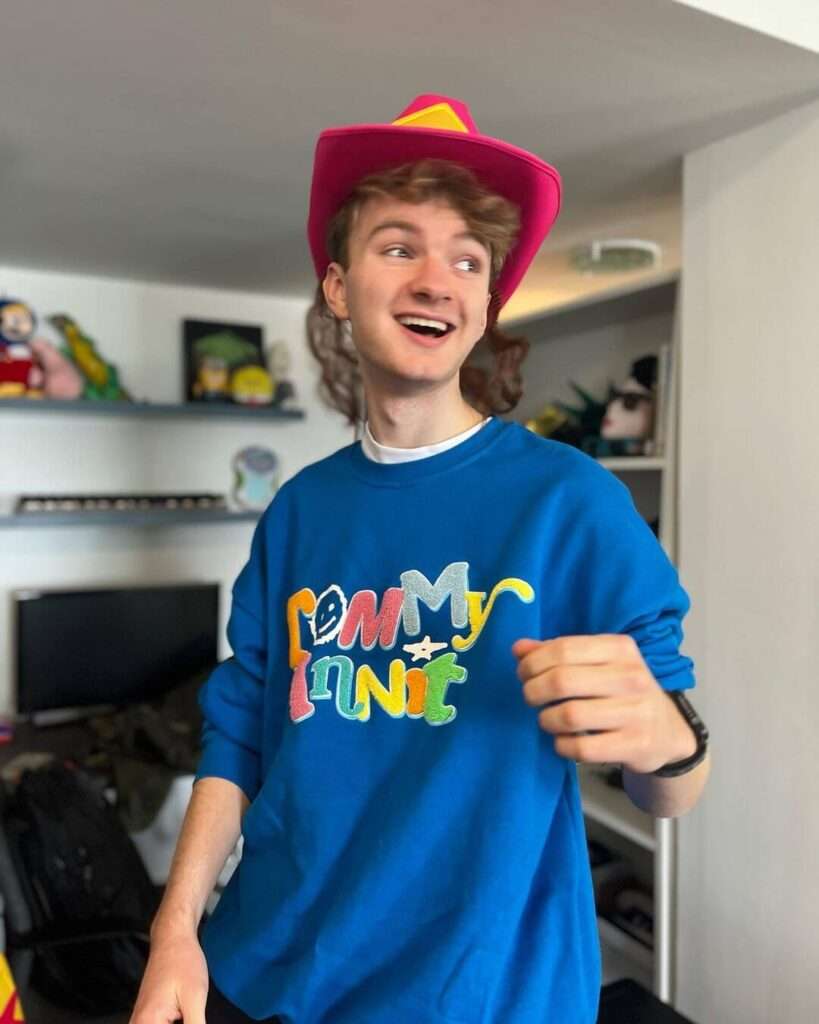Tommyinnit is wearing blue shirt and cap or smiling while posing for the picture