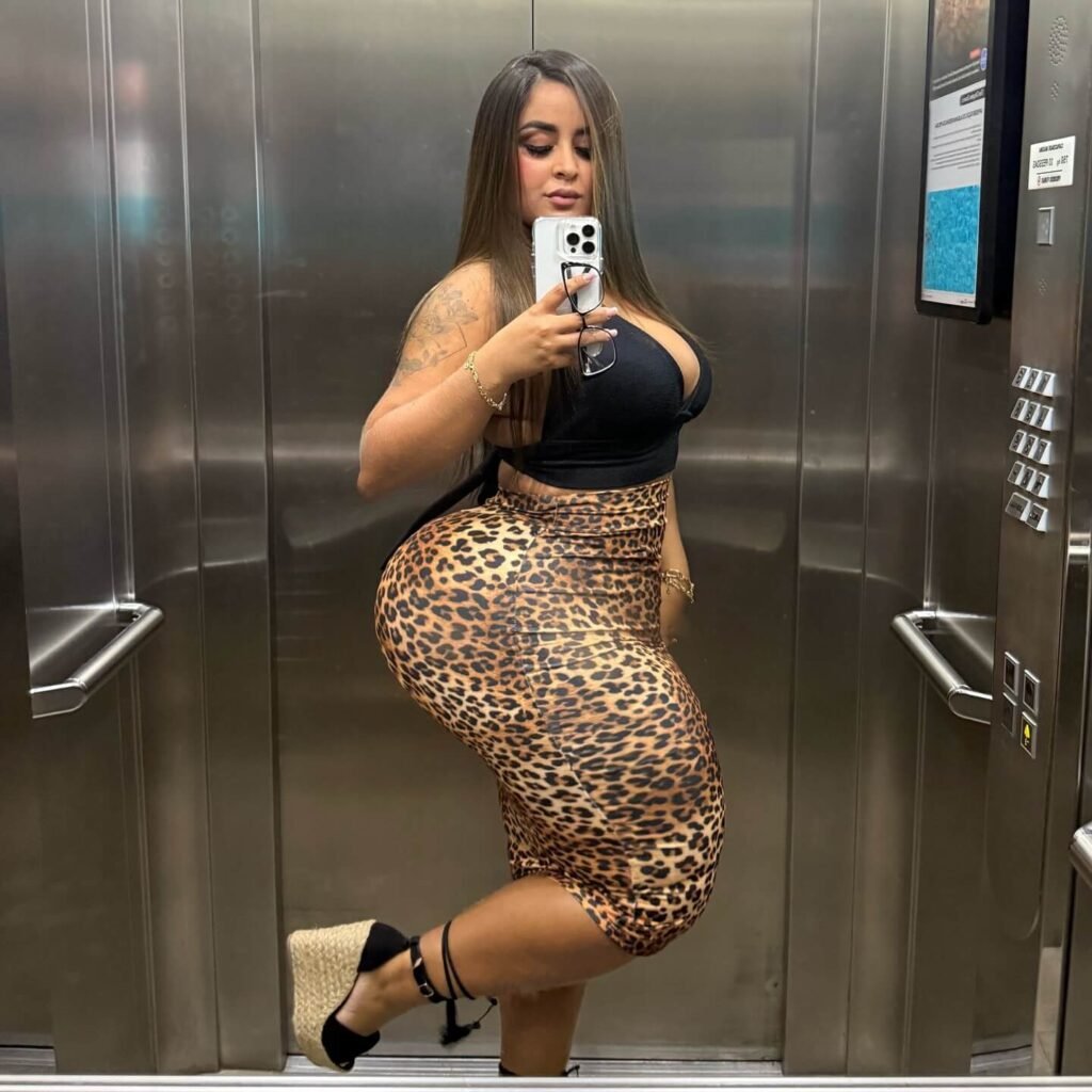 Dinalva Vasconcelos Wiki: Bio, Facts, Age, Height, Weight, Measurement, Photos; glamour Model 11 Dinalva Vasconcelos taking a mirror selfie in an elevator wearing a leopard print skirt and black top, showing off her hourglass silhouette.