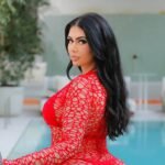 Sammyy02k posing by the pool in a bold red netted cover-up, highlighting her curves with long black hair and confident expression.