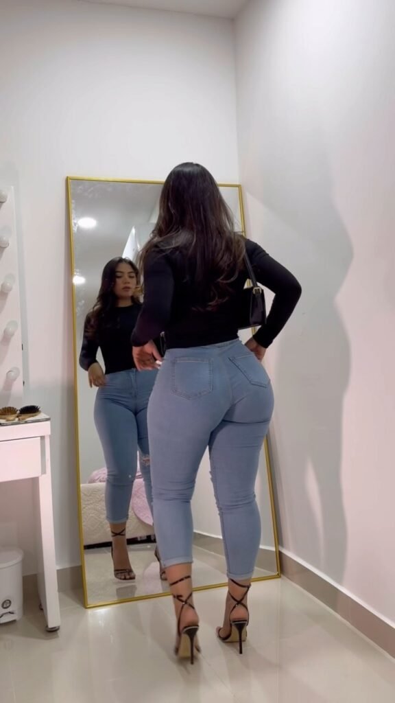 Stunning Latina model Angel Lopez in a black top and light blue skinny jeans, showcasing plus-size fashion for hourglass body shapes.
